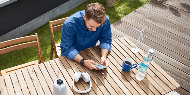 Ein Mann sitzt mit Smartphone in der Hand auf einer Terrasse