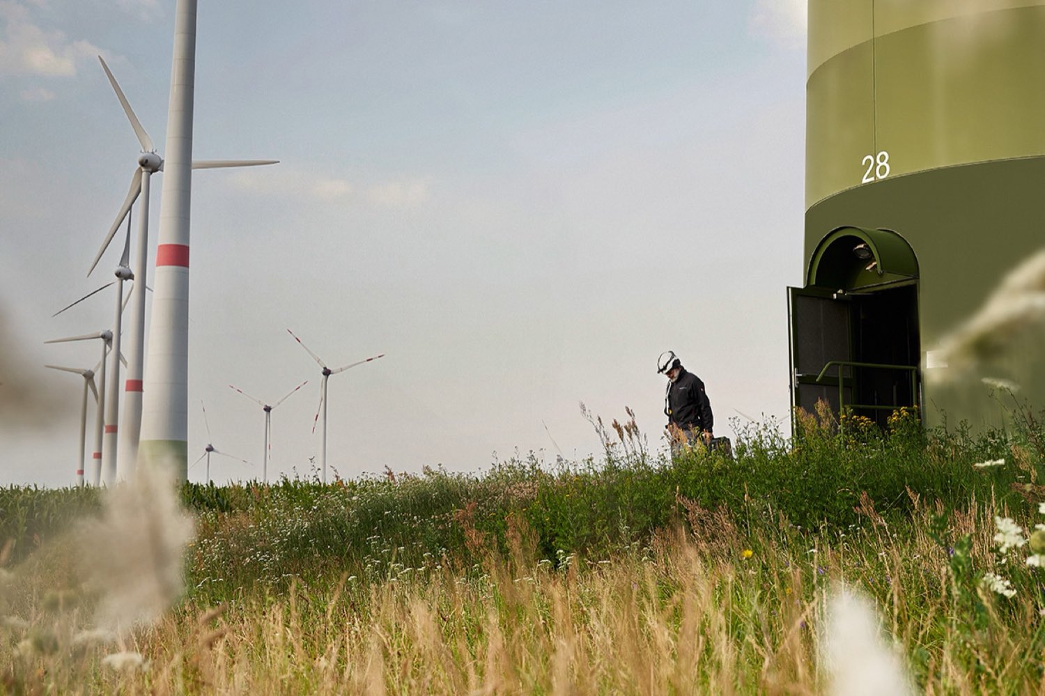 Mann steht zwischen Windrädern eines Windparks in Feldheim
