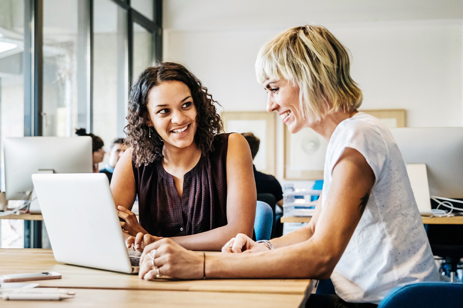 Zwei Frauen arbeiten gemeinsam am Laptop im modernen Büro