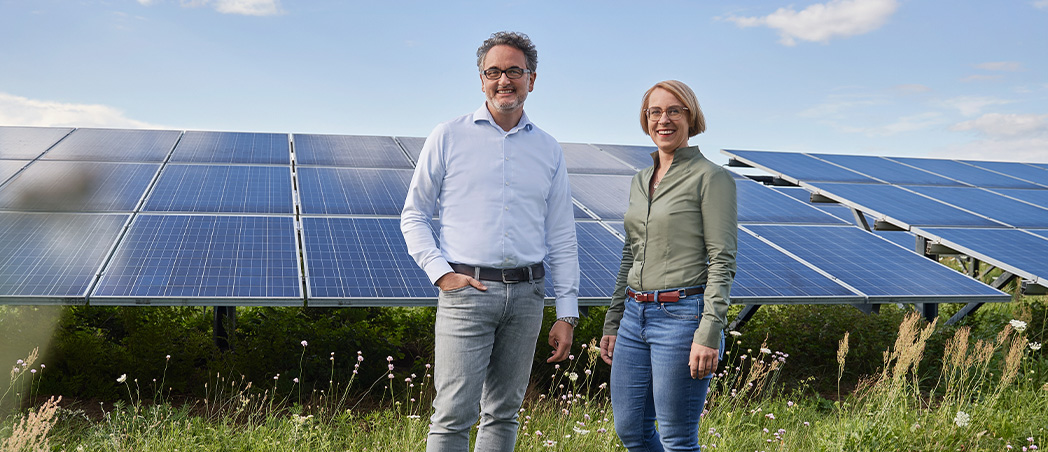 Zwei Menschen stehen vor einer PV-Freiflächenanlage
