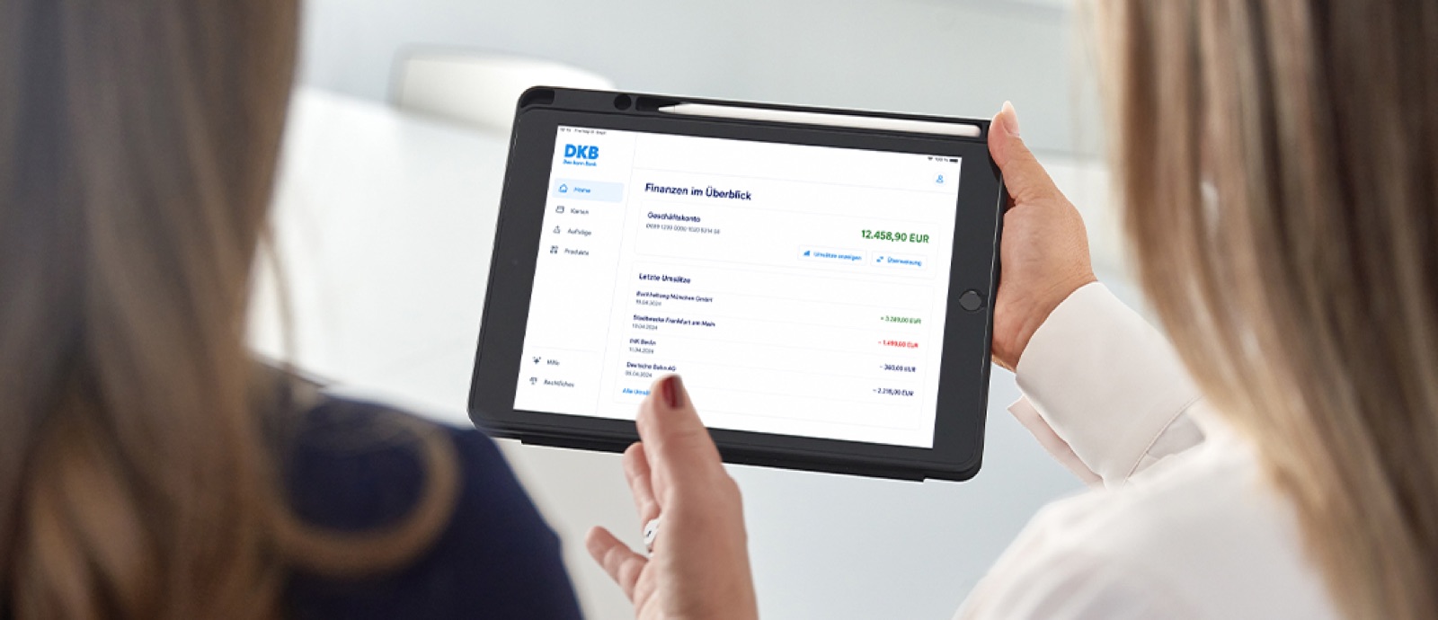 Zwei Personen betrachten DKB-Finanzübersicht auf Tablet