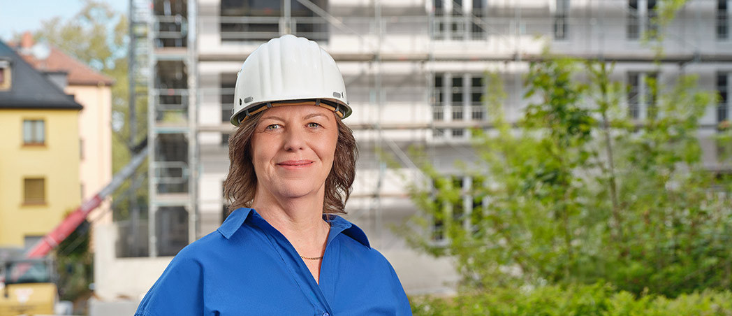 Cora Lehnert von der Wohnbaugenossenschaft vor einem Gebäude