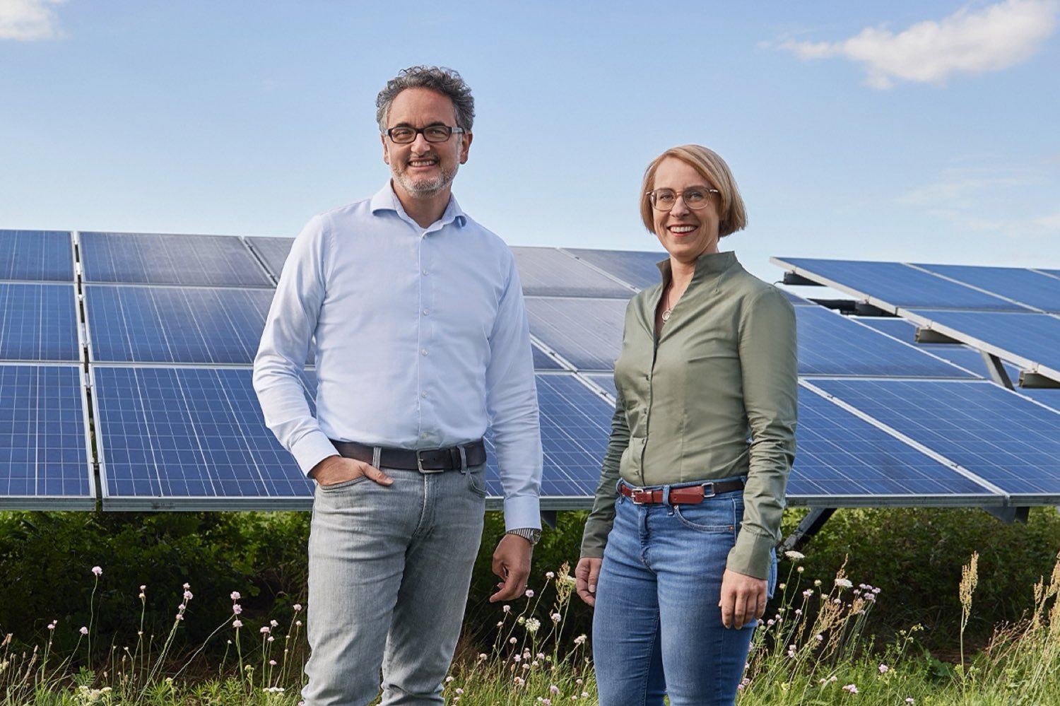 Zwei Menschen stehen vor einer PV-Freiflächenanlage